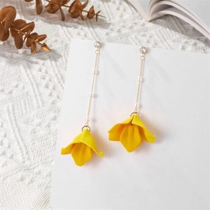 Detail of yellow flower drop earrings with gold chains and white faux pearls decor