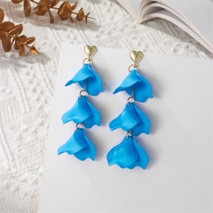 Macro view of tiered royal blue matte petal earrings with gold heart-shaped studs