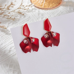 Macro detail of matte red petal earrings with iridescent beads on lace background