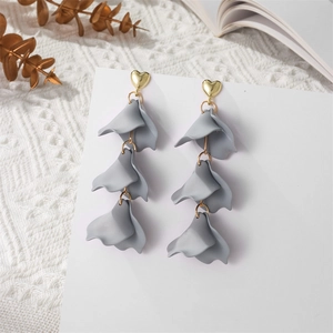 Close-up of matte grey leaf petal drop earrings with golden heart studs on display card