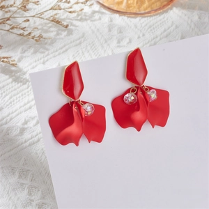 Detail of red petal earrings with gold edges and iridescent beads on white lace
