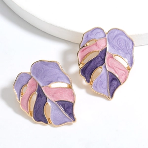 Golden monstera leaf earrings with purple enamel inlay on white pedestal background