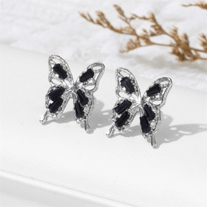 Macro shot of silver butterfly stud earrings with black crystals on white leather
