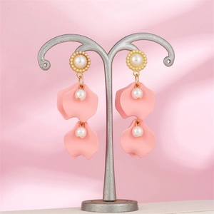 Macro detail of pink petal tassel earrings with pearl studs on a silk background
