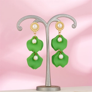 Close-up of green petal drop earrings with pearls on a silver jewelry stand