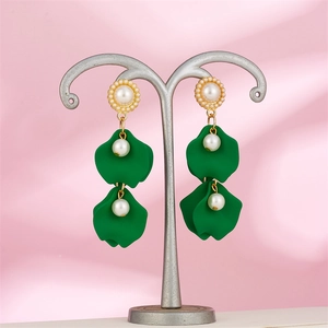 Detail of vintage long drop earrings with green resin petals and elegant white pearls