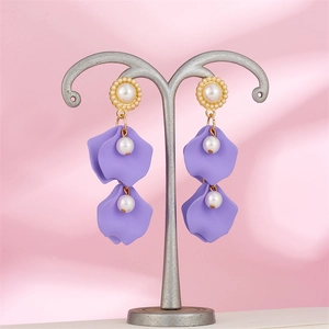 Detail of long pearl tassel earrings featuring lavender petals on a metal stand