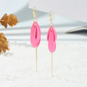 Close-up of pink petal earrings with gold tassels and rhinestone details on white lace