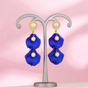 Retro long earrings with matte blue petals, pearls and gold loops on a jewelry stand