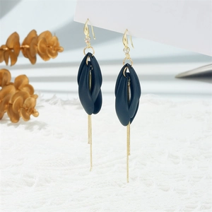 Detail of long tassel earrings featuring black resin petals and gold chain fringe