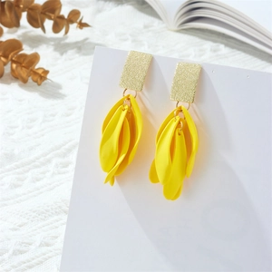 Detalle de pendientes largos con pétalos amarillos mate y acabado de metal dorado
