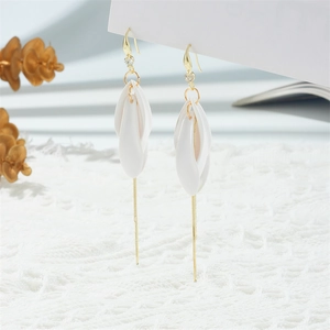 Close-up of elegant floral drop earrings with matte white petals and long gold tassels