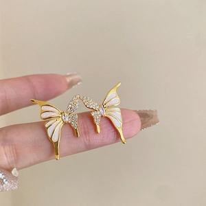 Elegante Schmetterling Ohrringe mit weißem Emaille und Kristallen an der Hand
