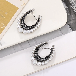 Detailed macro view of silver horseshoe earrings with black rhinestones and white pearls