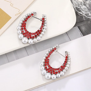 Close-up of C-shaped earrings with red rhinestones and gradient pearls on silver base