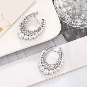 Detailed view of silver U-shaped earrings with pearls and colorful rhinestones