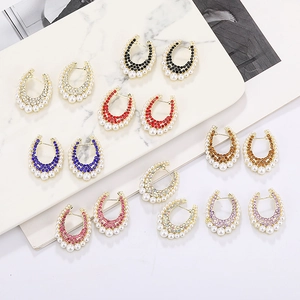 U-shaped earrings with colorful rhinestones and white pearls on marble display