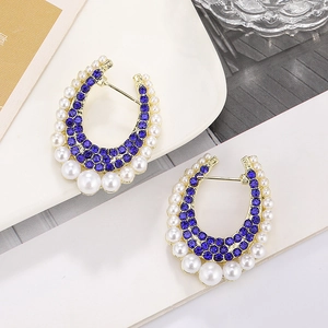 Detail of U-shape earrings with deep blue crystals and gradient white pearls in gold