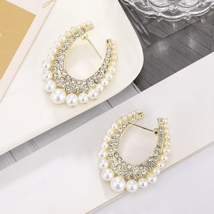 Macro shot of U-shaped gold earrings with pave rhinestones and gradient faux pearls