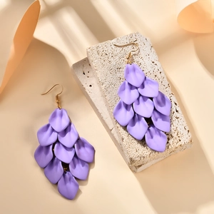 Detail view of purple layered petal fringe earrings on a natural stone base