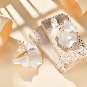 Detail view of pearlescent petal earrings with gold core on natural stone texture
