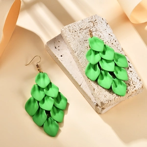 Detail of emerald green layered petal drop earrings on a natural stone textured background