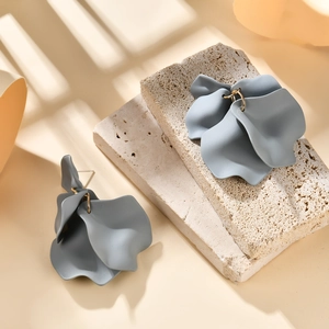Macro shot of grey petal drop earrings on stone slabs with shadow highlights