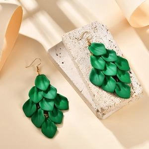 Close-up of matte green layered petal tassel earrings with golden ear hooks on stone