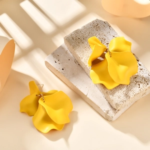 Macro detail of yellow petal earrings featuring matte finish and artistic shadow play