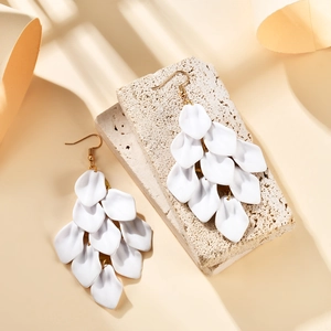 Detail of white matte layered flower petal tassel earrings on a natural stone base