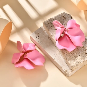 Elegant matte pink flower petal earrings on stone with sunlight and blind shadows