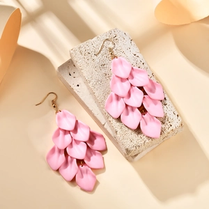 Detail of pink layered petal tassel earrings with matte finish on a stone texture