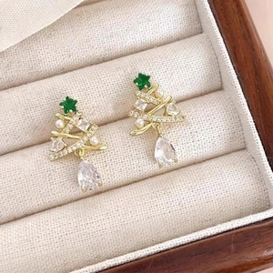 Elegant gold Christmas tree earrings with sparkling crystals and pearls on white velvet