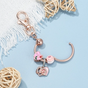 Rose gold MOM keychain with pink enamel heart charm and infinity symbol on blue background