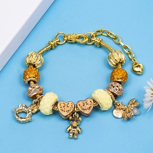 Golden snake chain charm bracelet with bear heart and bee pendants on blue background