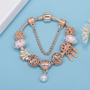 Rose gold snake chain bracelet with pearl and shell charms on blue background