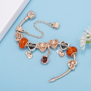 Silver-plated DIY charm bracelet with Mom heart charms and orange glass beads on blue backdrop