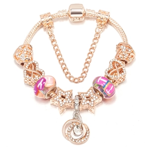 Bracelet maille serpent or rose avec charms cristal, étoiles et chaîne de sécurité sur blanc