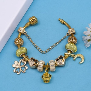 Gold beaded charm bracelet with four-leaf clover, heart, and crown on a snake chain