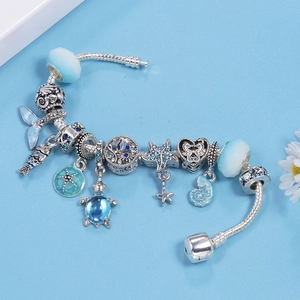 Silver ocean theme charm bracelet featuring blue glass beads and sea turtle pendants