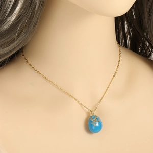 Détail macro du pendentif œuf Fabergé doré avec émail bleu ciel et zircons