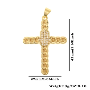 Macro detail of a gold cross pendant featuring Hamsa hand and white cubic zirconia