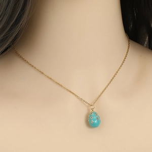 Detail of light blue egg pendant on 18K gold plated chain worn on a mannequin