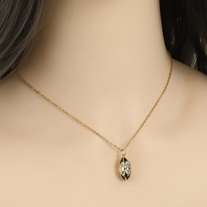 Detail of gold necklace with eye-shaped black enamel pendant and inlaid crystals