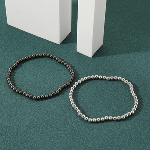 Minimalist beaded bracelets in silver and gun black finish on a dark textured background