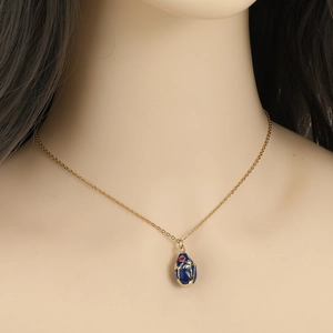 Exquisite 18K gold-plated necklace featuring a blue enamel egg pendant with gold scroll patterns