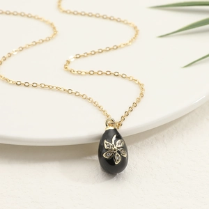 Elegant gold necklace with a black egg-shaped pendant featuring zircon flower patterns