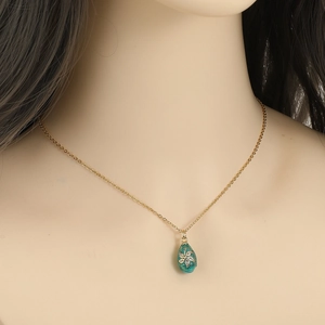Detail of a vintage-style blue enamel drop pendant with a gemstone flower on a gold chain
