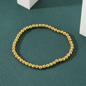 Polished 18K gold beaded bracelet for women on a dark green textured background