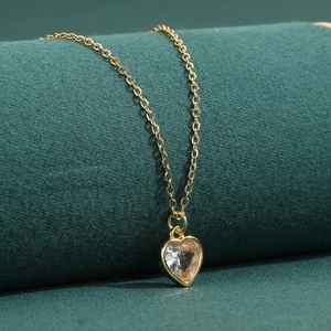 Elegante goldene Halskette mit Herzanhänger und funkelndem Kristall auf dunklem Samt